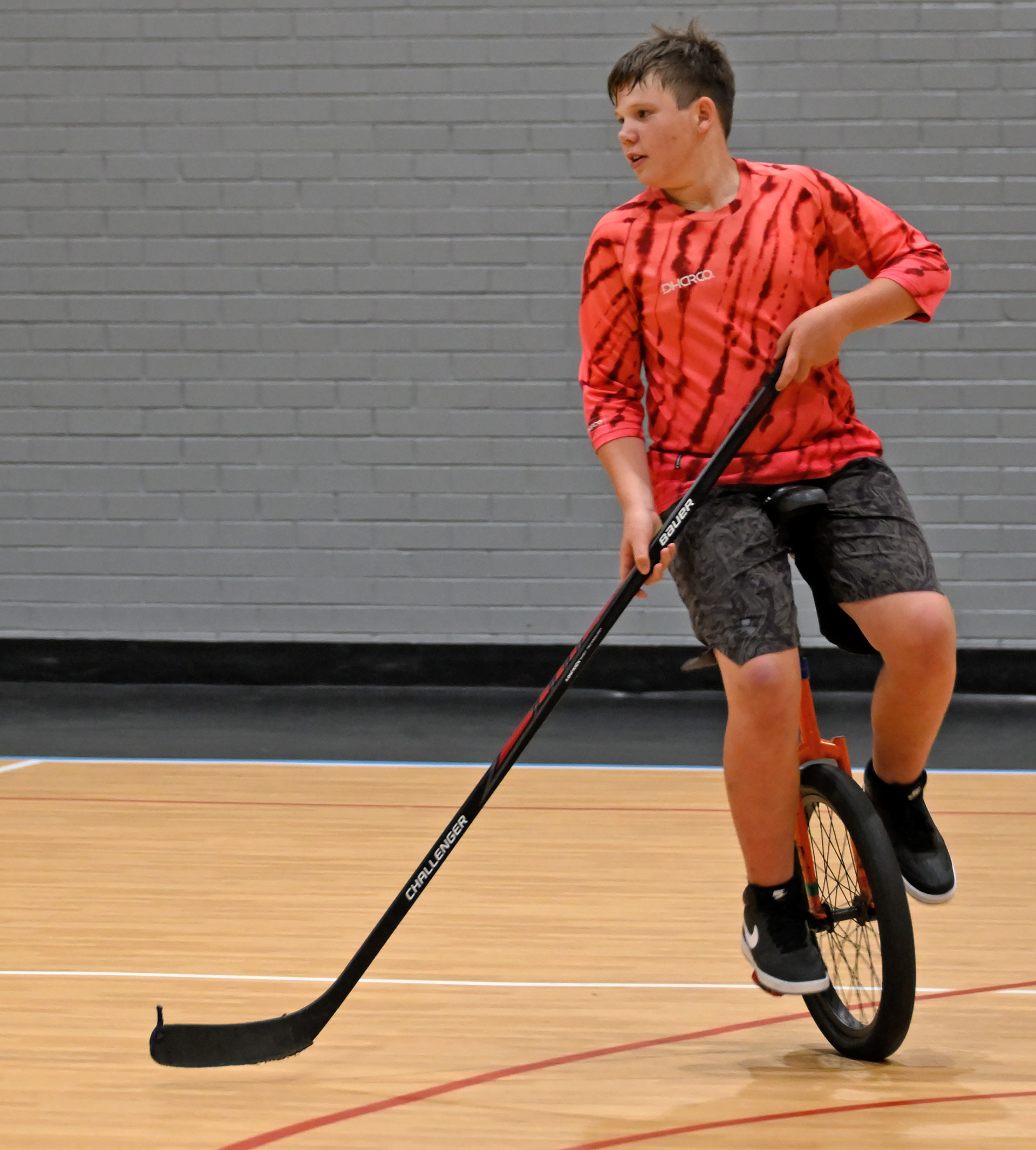 A boy on a unicycle with a hockey stick